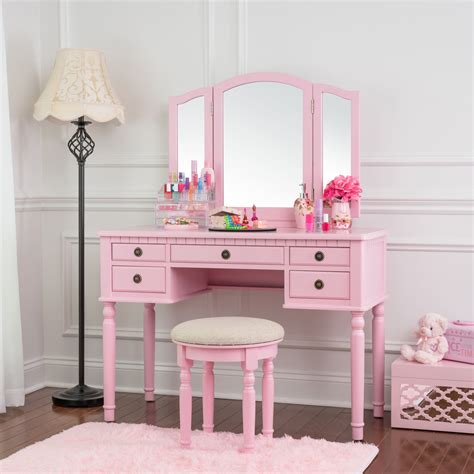 Pink vanity set - The set includes a pink vanity table, a tri-fold mirror, and a matching stool. Made from solid and engineered wood, the vanity features a single drawer with a knob handle for storing accessories and a tabletop that can support up to 100 lbs. The coordinating stool has a weight capacity of 50 lbs. and is finished in a matching pink hue.